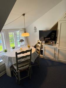 a dining room with a table and chairs and a television at Friesenhof Süderende Apt.4 in Westerland