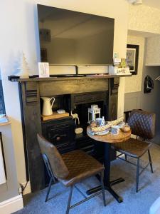 a table and chairs in a room with a fireplace at Cobweb Cottage in Patrington