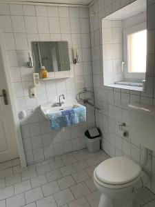 a white bathroom with a toilet and a sink at Eva Domizil in Laudesfeld +5 photos