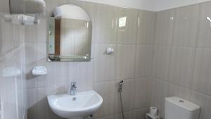 een badkamer met een wastafel, een toilet en een spiegel bij Surf reef guest house in Mirissa