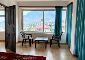 a living room with a table and chairs and a large window at Hotel Bharmour View in Brāhmaur