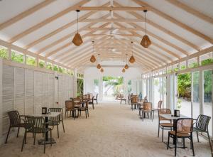 a dining room with tables and chairs and windows at Arena Blanca in Rasdhoo
