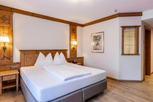 a bedroom with a large white bed and a desk at Landhaus Grünau in Wals