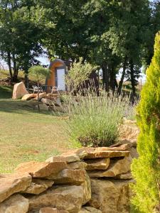a stone wall in front of a field with a cabin at POD Nature 2 in Chazelles