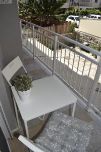 a white bench sitting on a balcony with a plant at Floor in Alexandroupoli