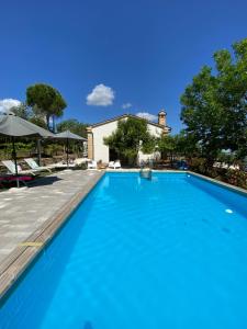a large blue swimming pool with a house in the background at Agriturismo Fontelini in Cingoli