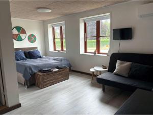 a bedroom with a bed and a couch and windows at VikingBnB in Kirke Såby
