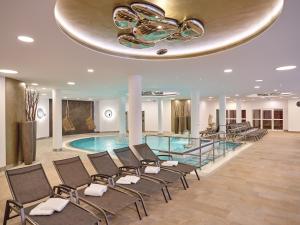 a hotel lobby with a pool and chairs and a chandelier at MAXIMILIAN Grand Hotel in Bad Griesbach