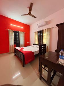 a bedroom with red walls and a bed and a table at Baylio Homestay Varkala in Kappil