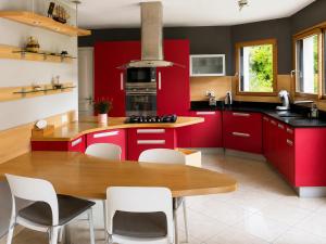 a kitchen with red cabinets and a wooden table at Pavillon des Chouettes in Brech