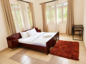 a bedroom with a bed and two windows and a red rug at MUTIMA VILLA in Jinja