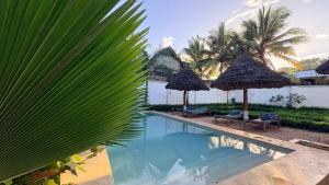 a pool with umbrellas and chairs next to a resort at NoyaAfrika Kendwa Boutique in Kendwa