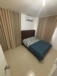 a small bedroom with a blue bed and curtains at Arellano Residence in Batangas City