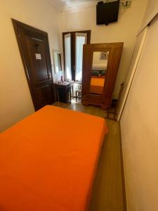 an orange bed in a room with a mirror at Hotel del Corso in Sestola