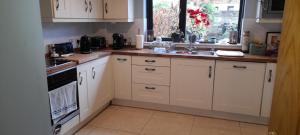 a kitchen with white cabinets and a sink and a window at Double Bed in Loft Space with En Suite in Loughrea