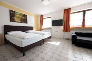 a bedroom with two beds and a chair and windows at Gästehaus Willanzheim in Willanzheim