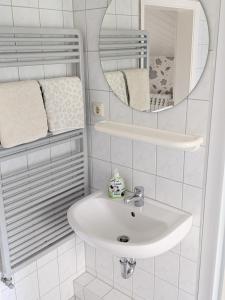 a white bathroom with a sink and a mirror at Zum Häusler-Glück in Biendorf