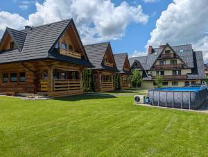 a log home with a yard and a swimming pool at Janulkowe Domki in Zakopane