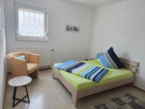 a bedroom with a bed and a chair and a window at Ferienhaus Maria in Breitengüßbach