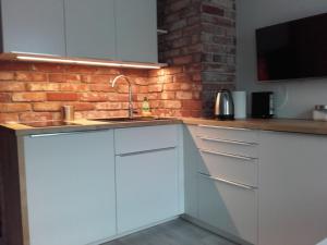 eine Küche mit weißen Schränken und einer Ziegelwand in der Unterkunft Studio Nowy Świat in Warschau
