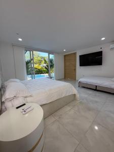 a white bedroom with a large bed and a tv at Quinta Samalu in Villavicencio