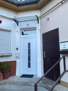 a white house with a black door and stairs at Andalics apartment in Kaposvár