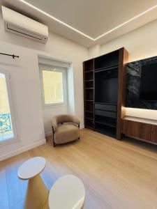 a living room with a tv and a chair and tables at Monaco - Menton Old Town - Climatisation - Seaview - Luxury rénovation in Menton