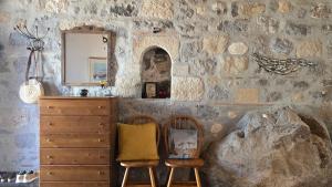 a room with two chairs and a dresser and a stone wall at Persephone's Home in Skala +13 photos
