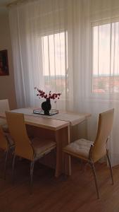a dining room table with chairs and a vase with flowers on it at WING 3 apartman ,,BC ,, in Jagodina