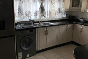 a kitchen with a sink and a washing machine at 4 Bed Gated House-Sleeps 8-Private Parking in Harare