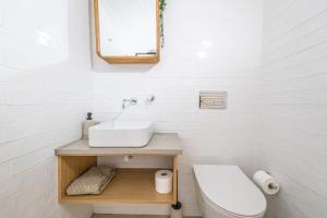 a white bathroom with a sink and a toilet at Casa Flora Tiny House in Fuzeta