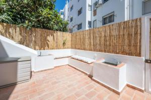 a patio with a bench and a fence at Casa Flora Tiny House in Fuzeta