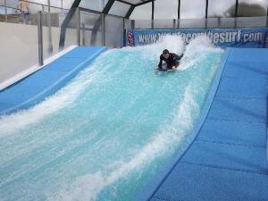 a man riding a wave on a wave board in a water park at Skipper's Place in Mortehoe