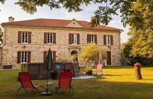 a house with chairs and an umbrella in the yard at Le Clos Cecile'Ann in Fréchou