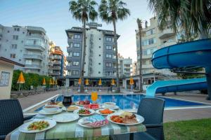 a table with plates of food next to a pool at Best Alanya Hotel in Alanya