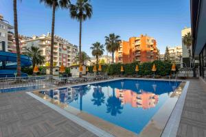 a swimming pool in a city with palm trees and buildings at Best Alanya Hotel in Alanya