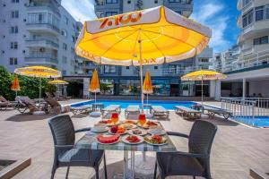 a table with food on it under a yellow umbrella at Best Alanya Hotel in Alanya