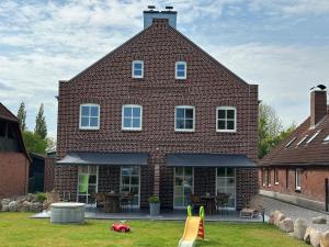 a large brick house with a playground in front of it at Linnebarg Hus 3 in Bisdorf