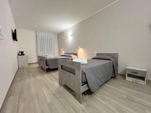 a bedroom with two beds and a desk and a television at Foresteria Lombarda Pavia in Pavia