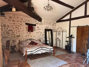 a bedroom with a bed and a stone wall at Le Clos Cecile'Ann in Fréchou