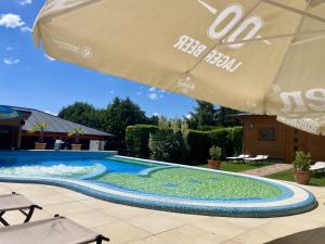 a swimming pool with an umbrella and a swimming pool at Hotel Mayer Alsóörs in Alsóörs