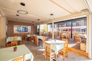 a restaurant with tables and chairs and windows at Hotel Primavera in Sarandë