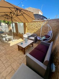 a patio with couches and a table and an umbrella at Sweet NiMa in Francavilla al Mare
