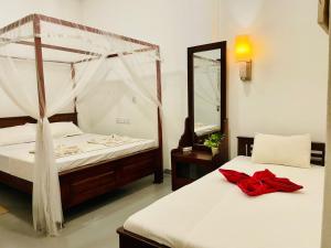 a bedroom with two beds and a mirror at Kingly Aroma in Arugam Bay