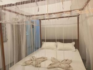 a bed with a canopy with bows on it at Kingly Aroma in Arugam Bay