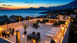 a rooftop patio with tables and chairs at night at Apartments and Studios Anicic in Utjeha