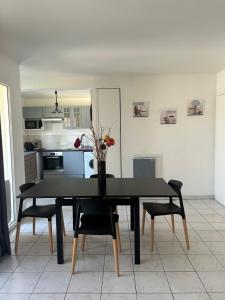 a black dining room table with chairs and a vase with flowers at appartement cosy tout équipe in Épinay-sur-Orge
