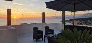 a patio with chairs and an umbrella and the ocean at Apartments and Studios Anicic in Utjeha