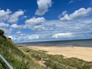 a view of a beach with people walking on it at Beach Chalet Home in Scratby