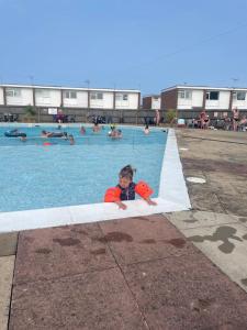 a young child is in a swimming pool at Beach Chalet Home in Scratby +5 photos